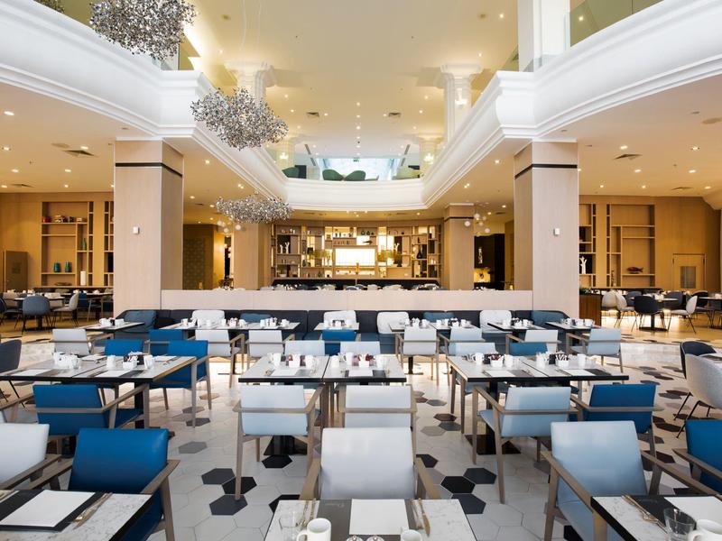 Amplia zona de comedor del hotel con asientos modernos y un diseño luminoso y abierto.