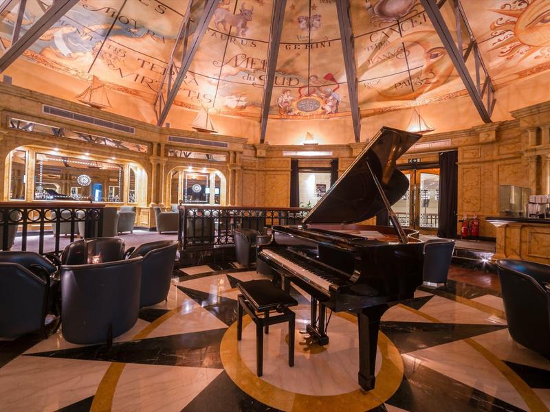 Interior elegante con piano de cola bajo una cúpula artísticamente decorada en un hotel.