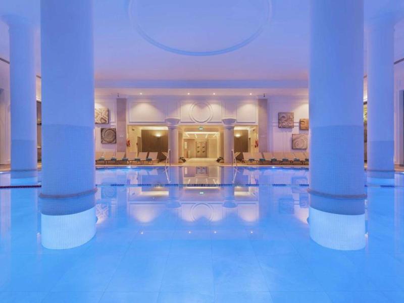 Piscina cubierta de hotel con columnas e iluminación relajante.