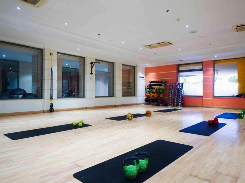 Sala de yoga luminosa con suelo de madera, esterillas y velas para relajación.