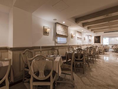 Un restaurant lumineux avec de nombreuses tables et des chaises en bois classiques aux tons chauds.