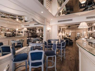 Restaurant élégant avec des chaises bleu rembourrées et des boiseries claires.