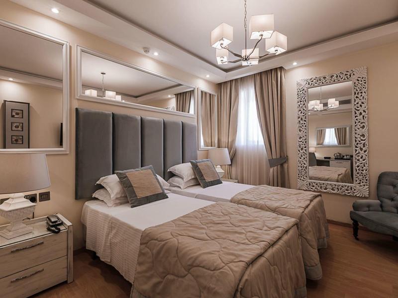 Nowoczesny pokój hotelowy z dwoma łóżkami, szafkami nocnymi i miejscem do siedzenia.