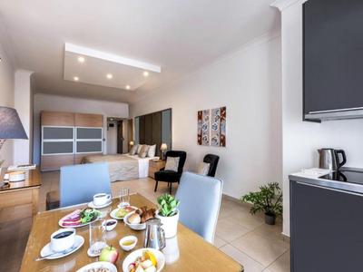 Nowoczesny salon z stołem jadalnym, sofą, krzesłami i otwartą aneksem kuchennym w jasnym pomieszczeniu.