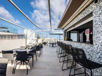 Taras na dachu z barem, krzesłami i stołami pod niebieskim niebem.