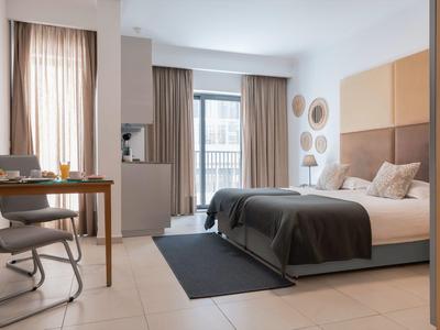 Modernes Hotelzimmer mit Doppelbett, Schreibtisch, Sitzbereich und großen Fenstern.