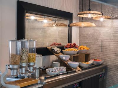 Buffet mit Getreidespendern, Obst und Frühstückszutaten in einem modernen Hotelbereich.