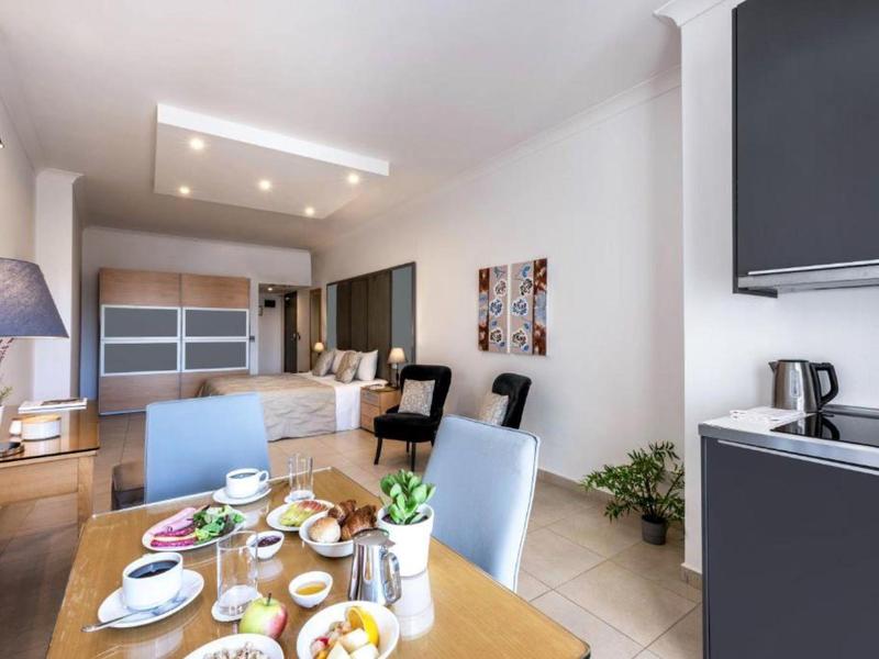 Nowoczesny salon z stołem jadalnym, sofą, krzesłami i otwartą aneksem kuchennym w jasnym pomieszczeniu.