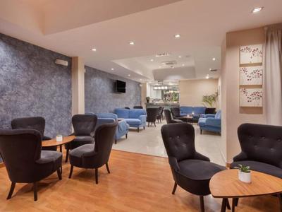 Accogliente area lounge con poltrone e tavoli in un interno di hotel moderno.