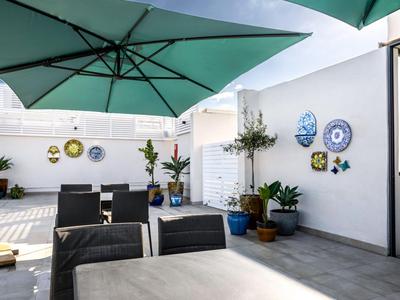 Moderner Hotel-Terrassenbereich mit Tischen, Stühlen, Pflanzen und Sonnenschirmen.