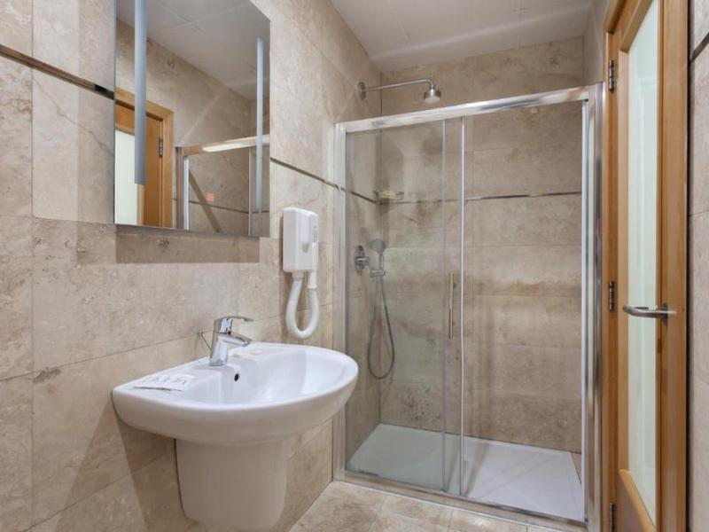 Bagno moderno con lavabo, specchio e doccia in vetro in toni neutri.