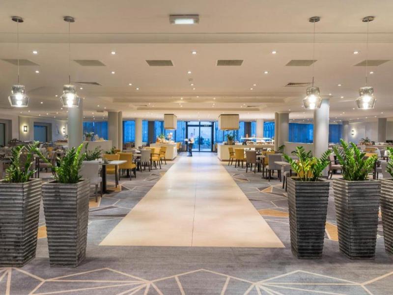 Velká světlá hotelová lobby s rostlinami a posezením na obou stranách.