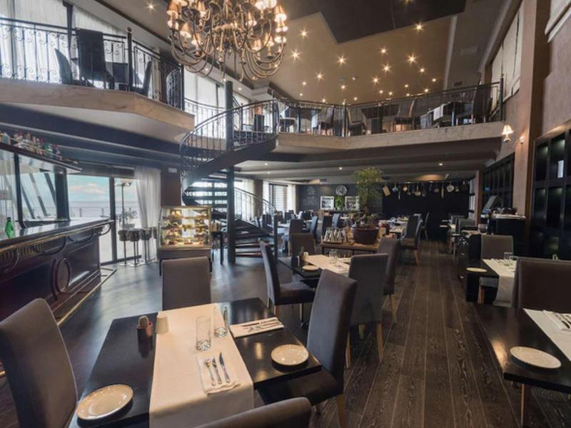 Elegantní restaurace se stylovým vybavením a lustry v vícepatrovém hotelu.