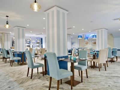 Helles, modernes Restaurant mit blauen Stühlen und weiß gestreiften Säulen in einem Hotel.