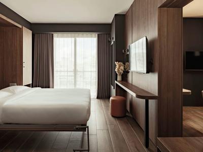 Modernes Hotelzimmer mit Doppelbett, großem Fenster und dunklen Holzmöbeln.