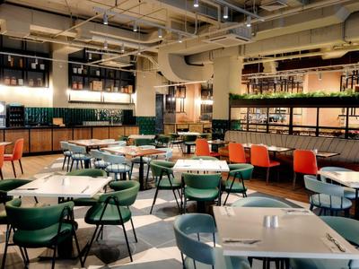 Ristorante moderno con sedie colorate e tavoli apparecchiati in un ambiente luminoso e spazioso.