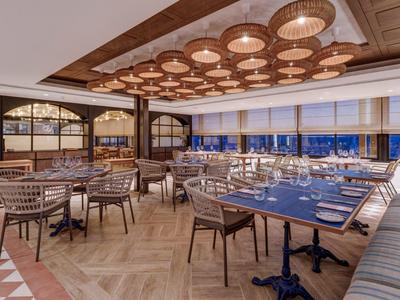 Elegantes Hotelrestaurant mit Holzdecken, großen Fenstern und stilvollen Sitzbereichen.