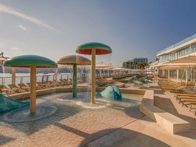 Lounge sulla terrazza con divani rosa e soffitto in legno, vista sulla città di giorno.