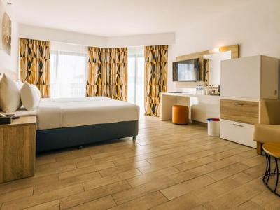 Geräumiges Hotelzimmer mit großem Bett, Holzfußboden und modernen Möbeln.