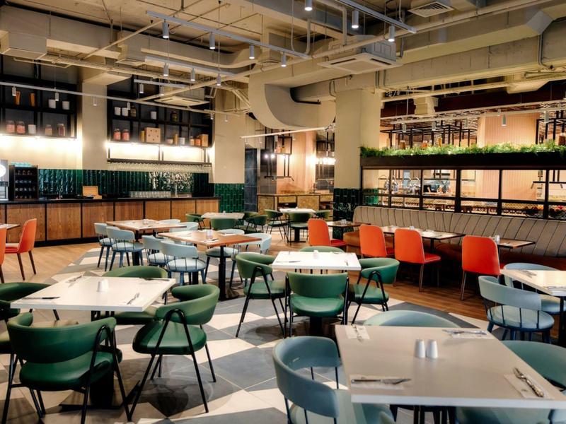 Modern eingerichteter Restaurantbereich mit farbigen Stühlen und hell beleuchtetem Ambiente.