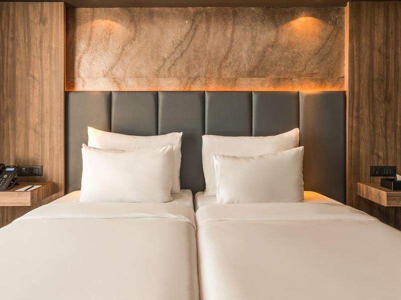 Modernes Hotelzimmer mit zwei Einzelbetten, Holzverkleidung und warmem Licht.