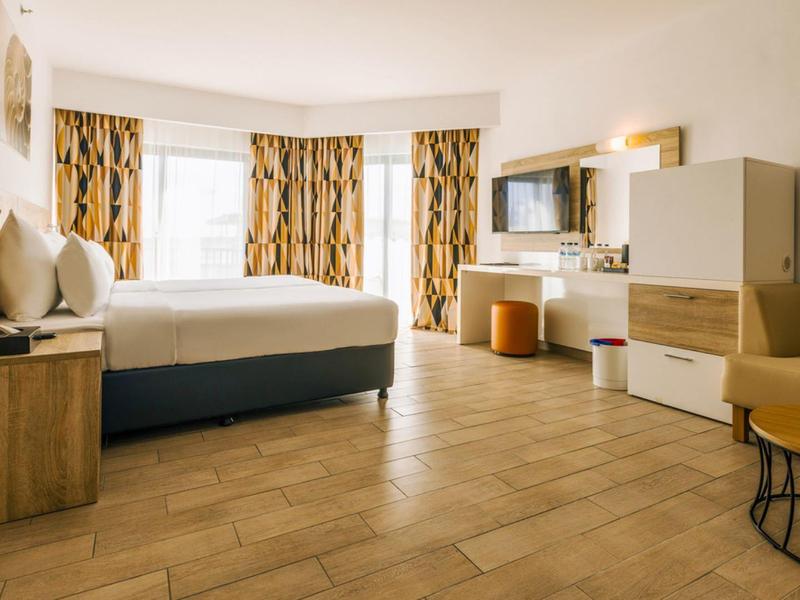 Geräumiges Hotelzimmer mit großem Bett, Holzfußboden und modernen Möbeln.