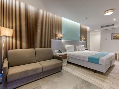 Moderne hotelkamer met tweepersoonsbed, bank en stijlvolle wandverlichting.