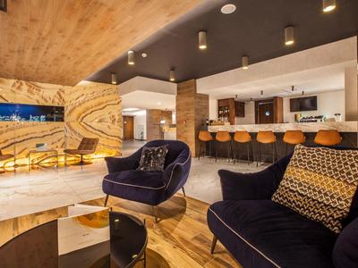 Moderne hotel-loungeruimte met stijlvolle fauteuils, barkrukken en warme houten decoratie.