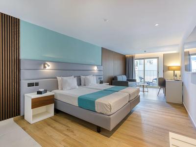 Modern hotelkamer met tweepersoonsbed, houten vloer en balkon met uitzicht.