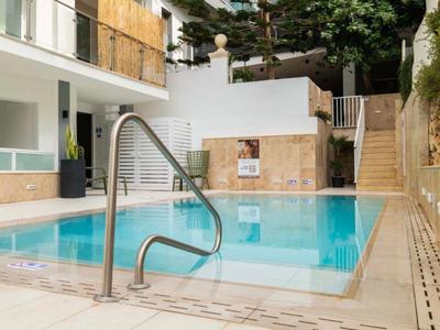 Kleiner Pool mit Metallgeländer und Treppe, umgeben von Natur und Gebäuden.