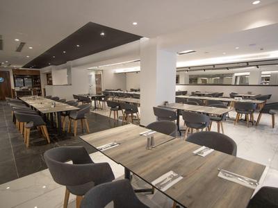 Moderne lichte eetruimte met houten tafels en gestoffeerde stoelen in een hotel.