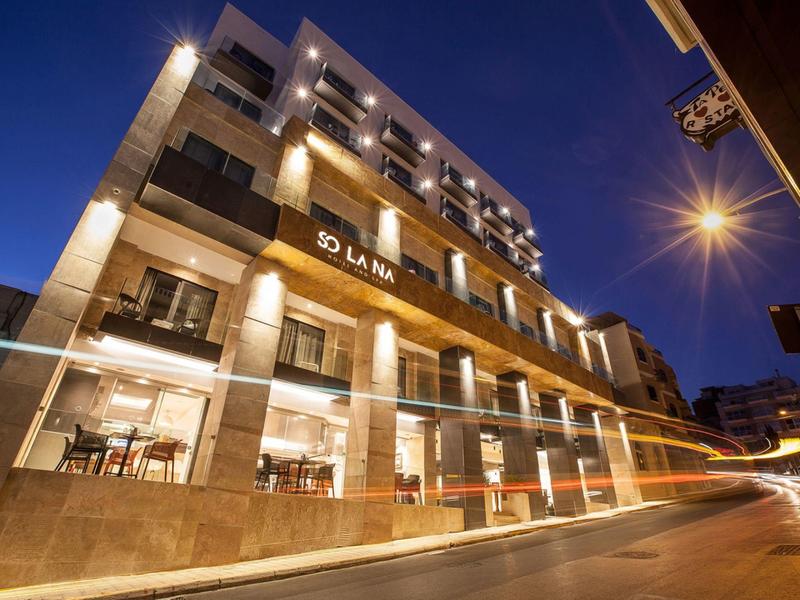 Modern hotelgebouw met verlichte gevel en straatbeeld 's nachts