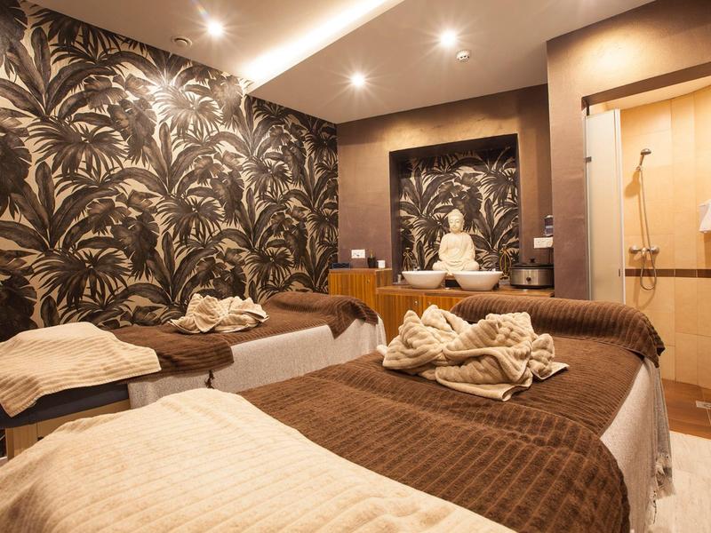 Modern wellnessruimte met massagetafels en rustgevende verlichting.