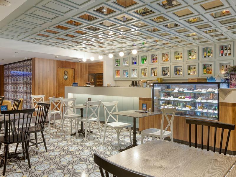 Modern café met lichte meubels, toonbank en versierde muren.