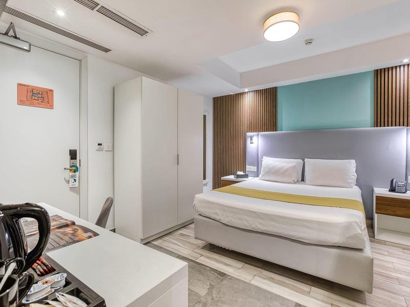 Modern hotelkamer met tweepersoonsbed, nachtkastjes, kledingkast en koffievoorzieningen.