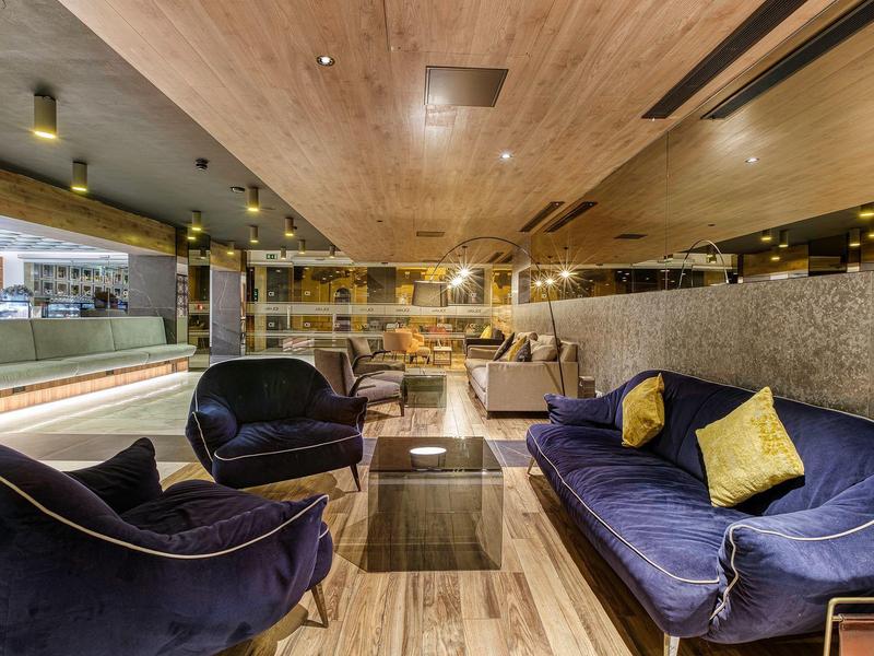 Moderne lounge met blauwe fauteuils, bank en een centrale tafel.