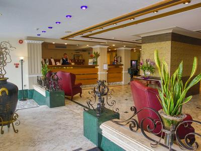 Luminosa recepción de hotel con plantas y sillones rojos de diseño moderno.