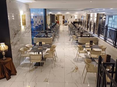 Área de comedor moderna y luminosa con mesas y sillas elegantes en un hotel.