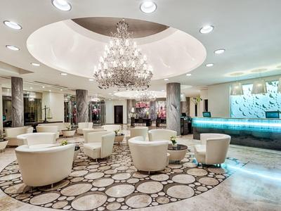 Moderner Hotel-Loungebereich mit Kronleuchter, runden Sesseln und einem dekorativen Teppich.