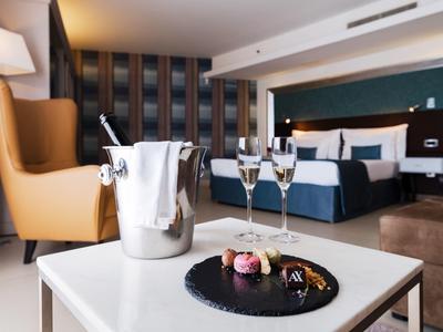 Elegancki pokój hotelowy z wygodnym miejscem do siedzenia, szampanem i deserem na stole.