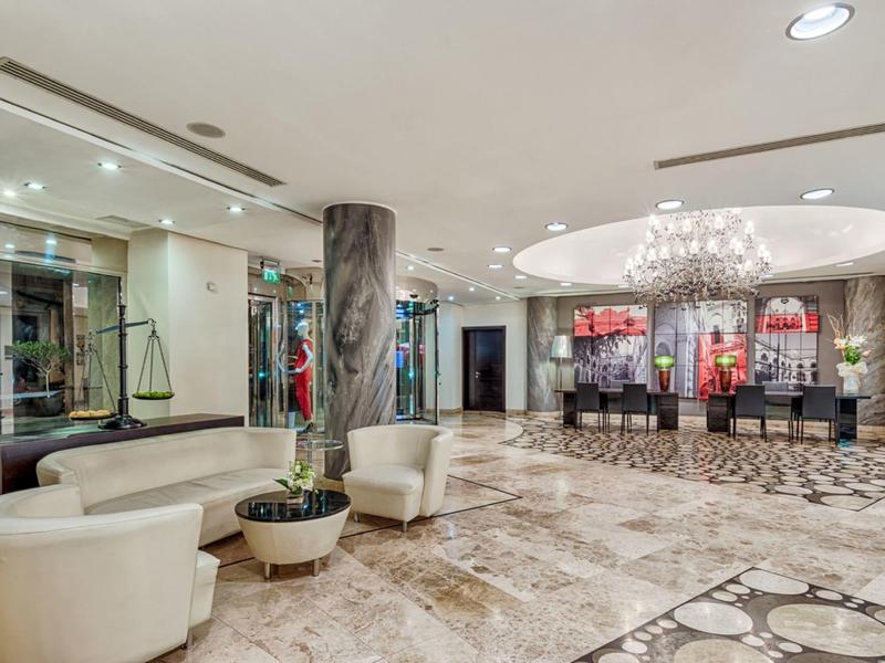 Jasna lobby hotelowa z wygodnymi fotelami, nowoczesnym oświetleniem i recepcją.