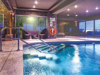 Hell beleuchteter Innenpool mit ruhigem Wasser und Panoramafenstern in einem Hotel.