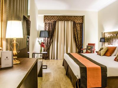 Elegantes Hotelzimmer mit großem Bett, Nachttischen und einem Fenster mit Vorhängen.