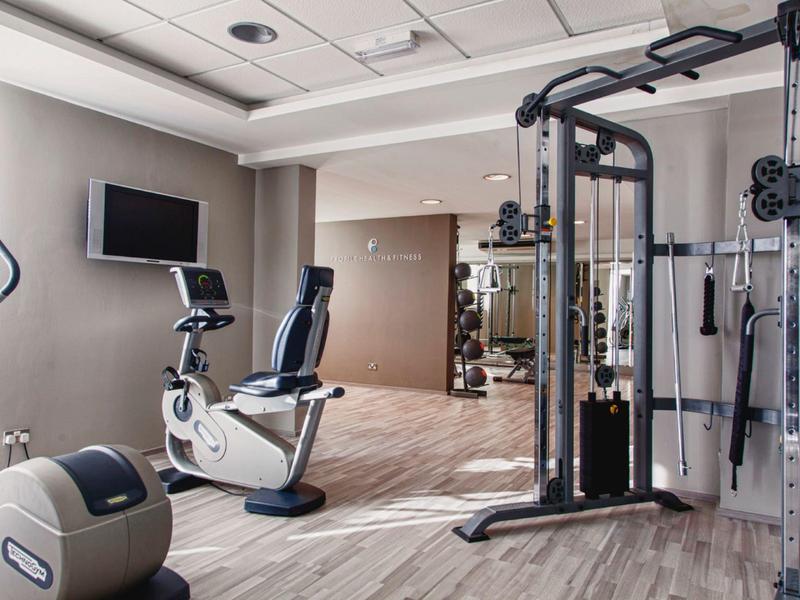 Moderner Fitnessraum mit Trainingsgeräten und hellem Holzboden in Hotelatmosphäre