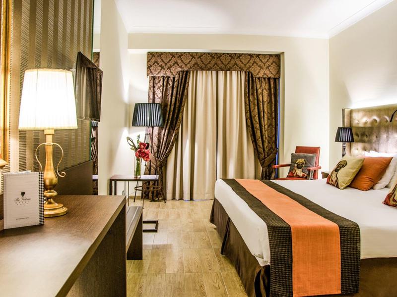 Elegantes Hotelzimmer mit großem Bett, Nachttischen und einem Fenster mit Vorhängen.