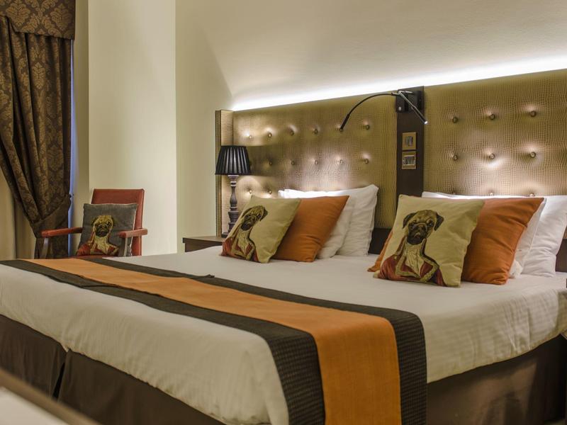 Gemütliches Hotelzimmer mit großem Bett, dekorativen Kissen und stilvoller Beleuchtung.