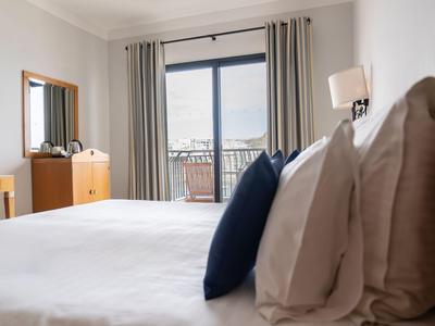 Helles, modernes Hotelzimmer mit großem Bett, Balkon und Blick auf Stadt.