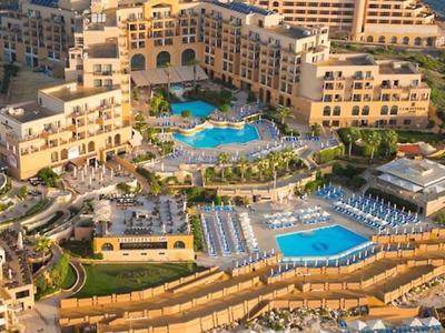 Großes Resort mit mehreren Pools, umgeben von Hotelgebäuden und Terrassen mit Blick aufs Meer.