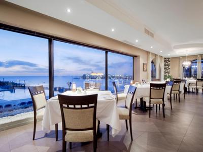 Elegante eetkamer met grote ramen met uitzicht op een waterkant bij zonsondergang.