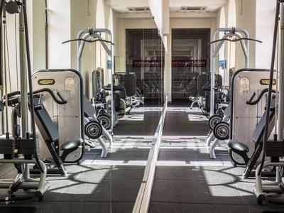 Heller und moderner Fitnessraum mit Trainingsgeräten und großen Fenstern.